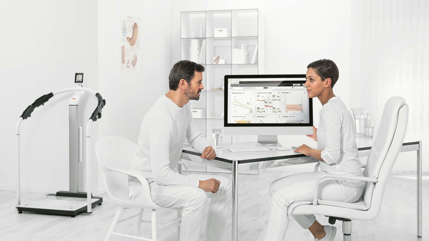 man in white dress shirt sitting on white chair in front of computer