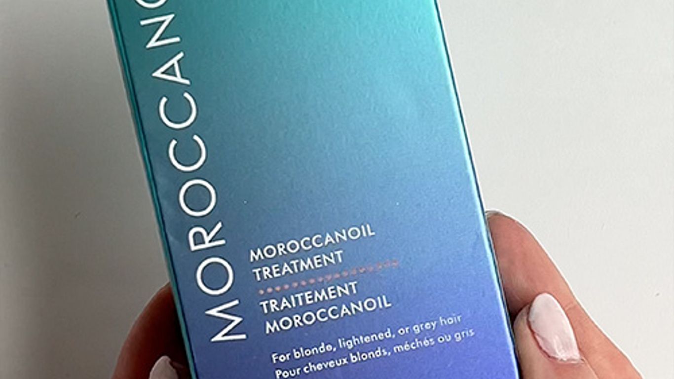 Hand holding a Moroccanoil Treatment box for light hair.