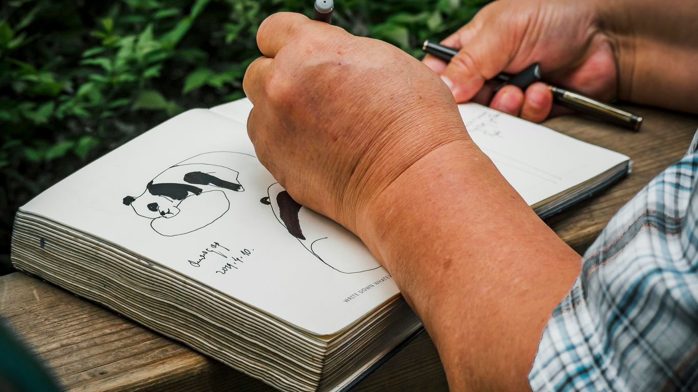 a person writing on a notebook with a pen