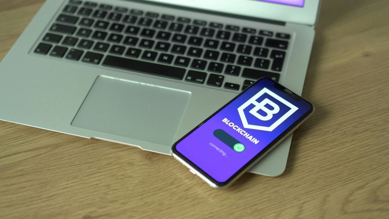 A laptop and smartphone displaying a blockchain application interface.