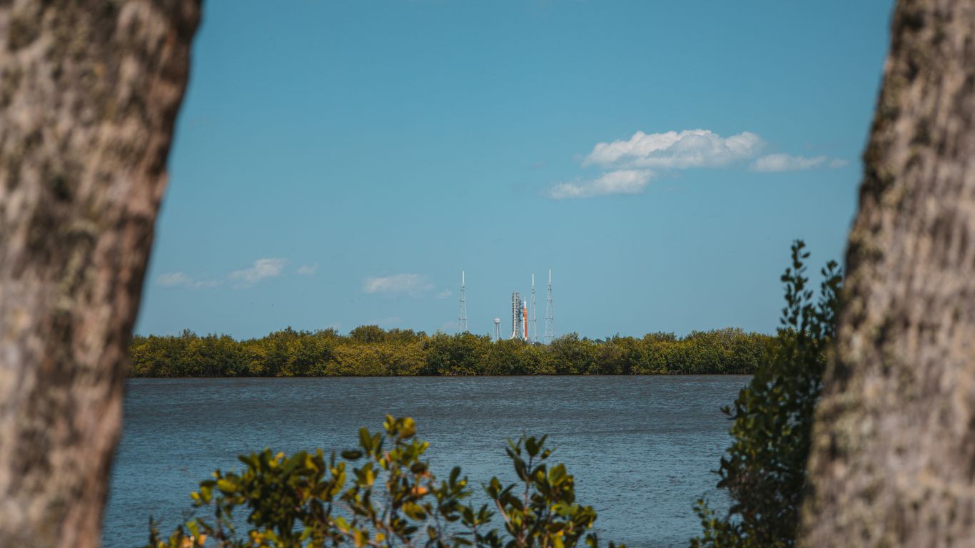 a body of water surrounded by trees and a blue sky