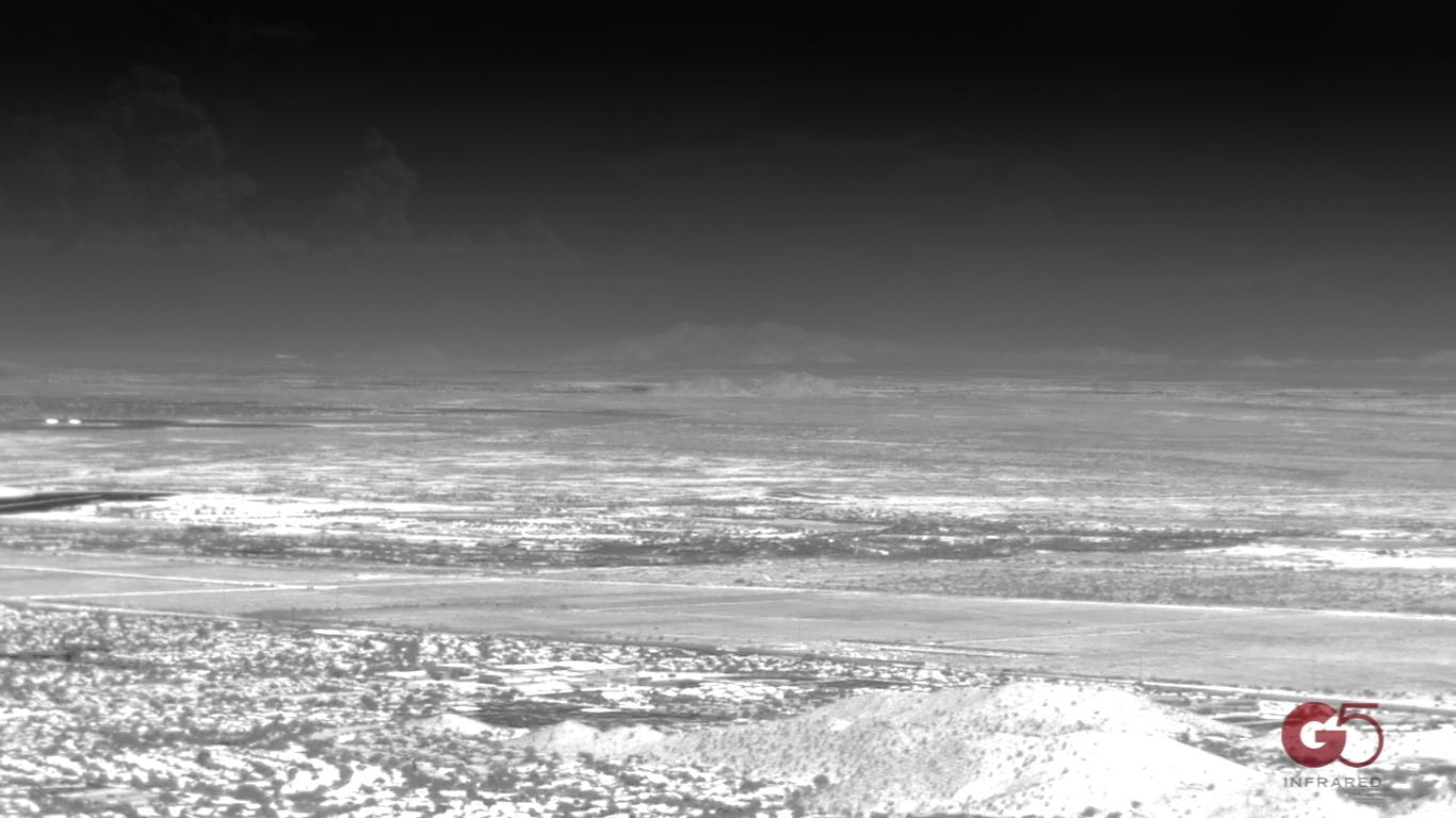 Infrared aerial view of a vast, flat landscape with distant mountains.