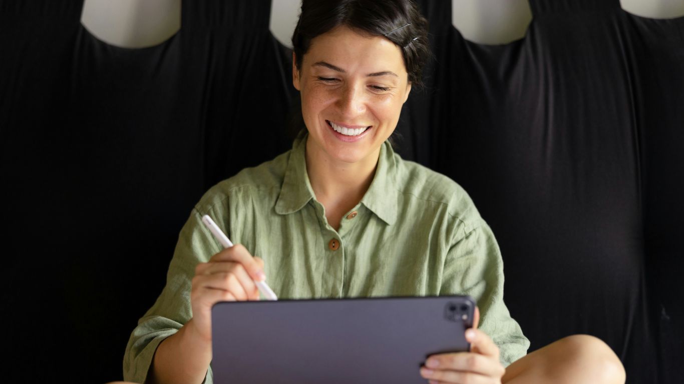 a woman sitting on the floor holding a tablet