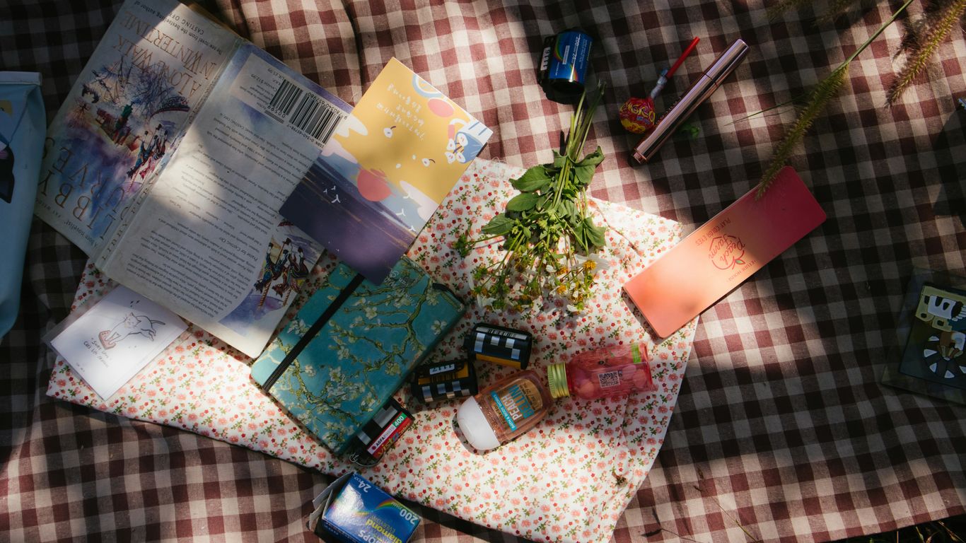 flowers and books on gingham sheet on grass