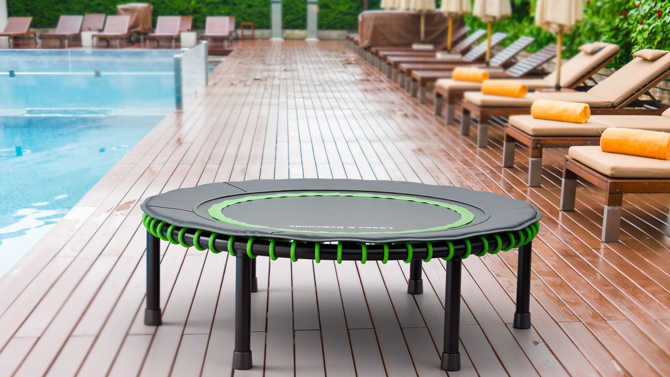 Small trampoline on poolside deck, surrounded by lounge chairs.