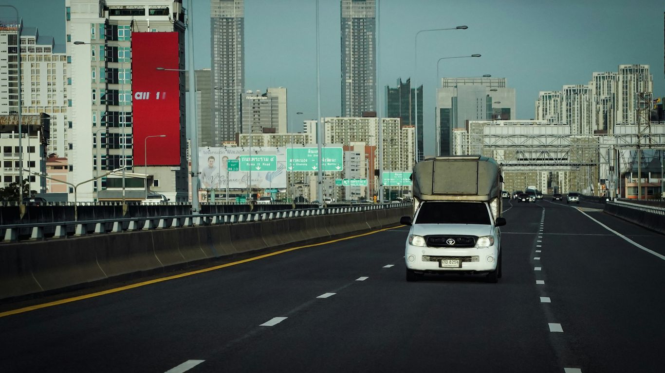 a white car driving down a highway next to tall buildings