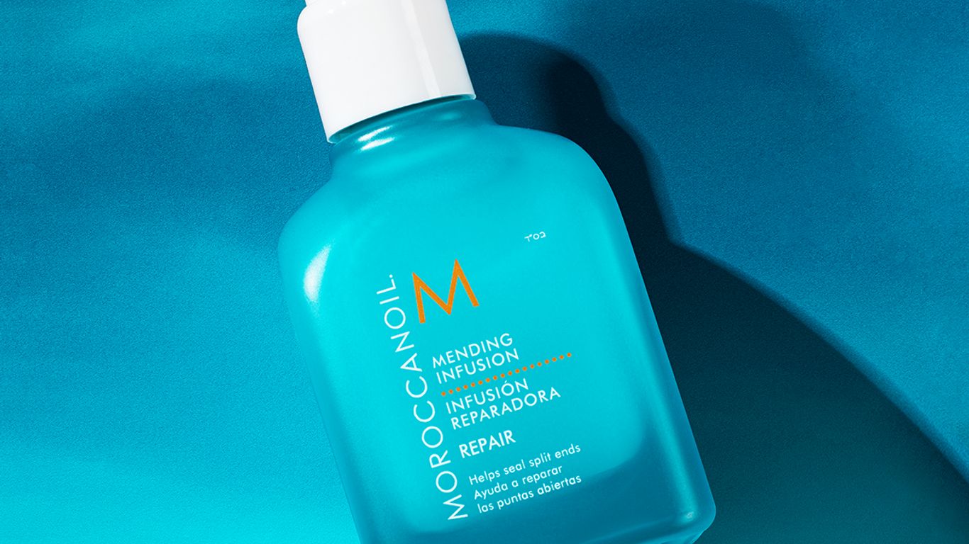 Bottle of Moroccanoil hair treatment on a blue background.