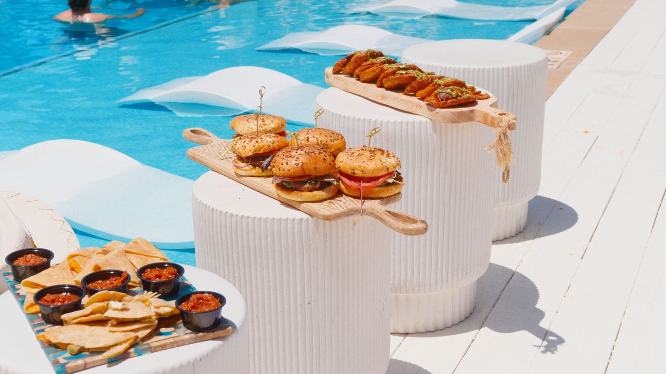 Burgers and quesadillas served poolside with salsa and a person swimming.