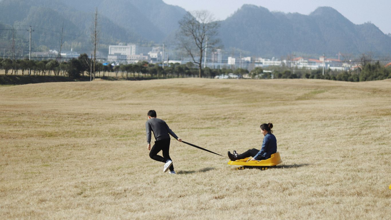man pulling wagon with woman riding on it
