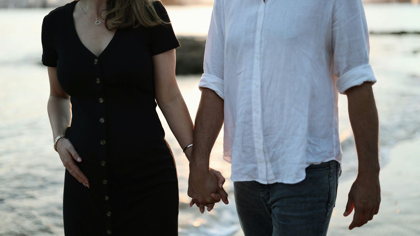 a man and a woman holding hands on the beach