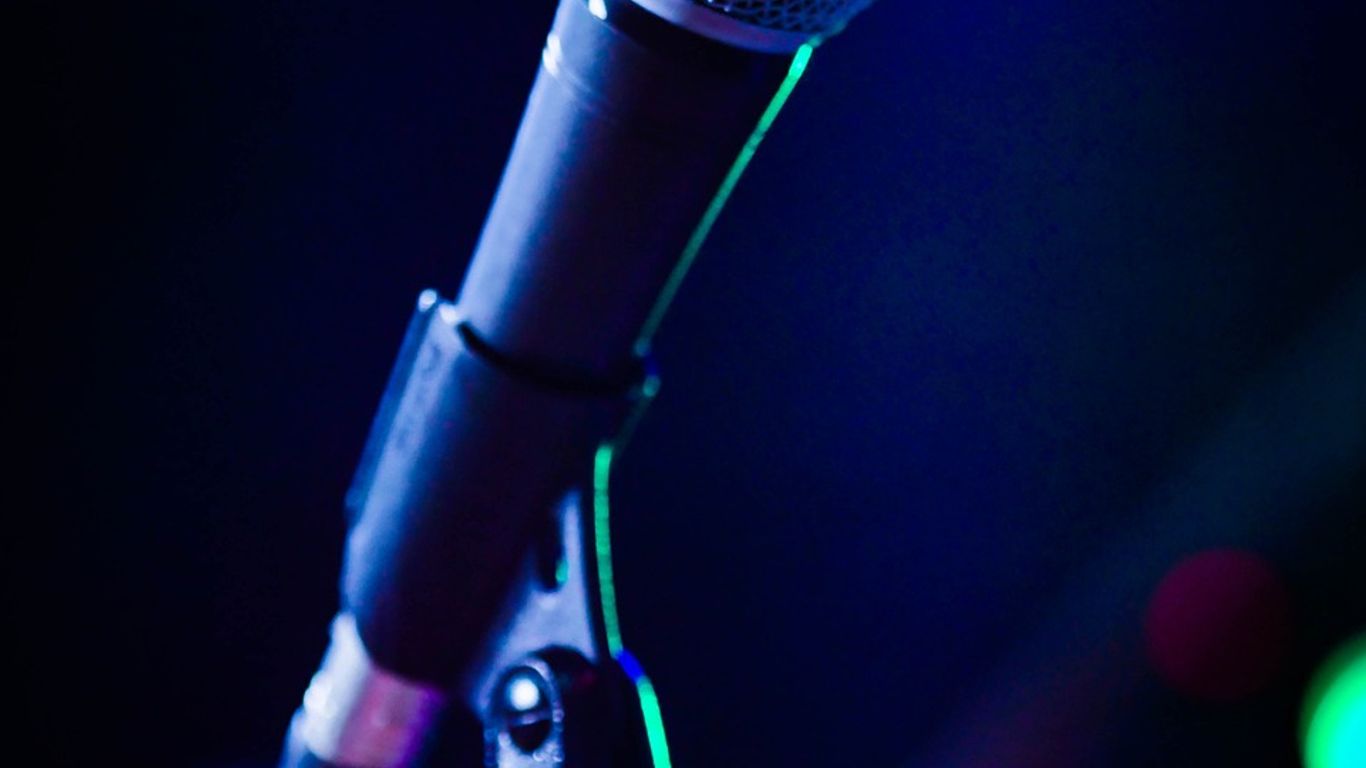 A close-up of a microphone with colorful blurred lights.
