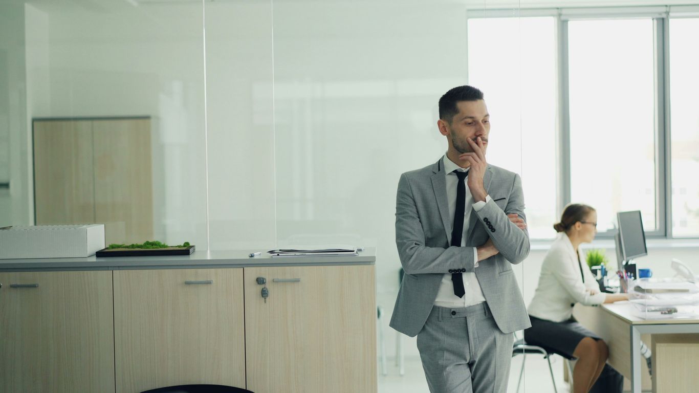 Man in suit thinking in modern office environment.