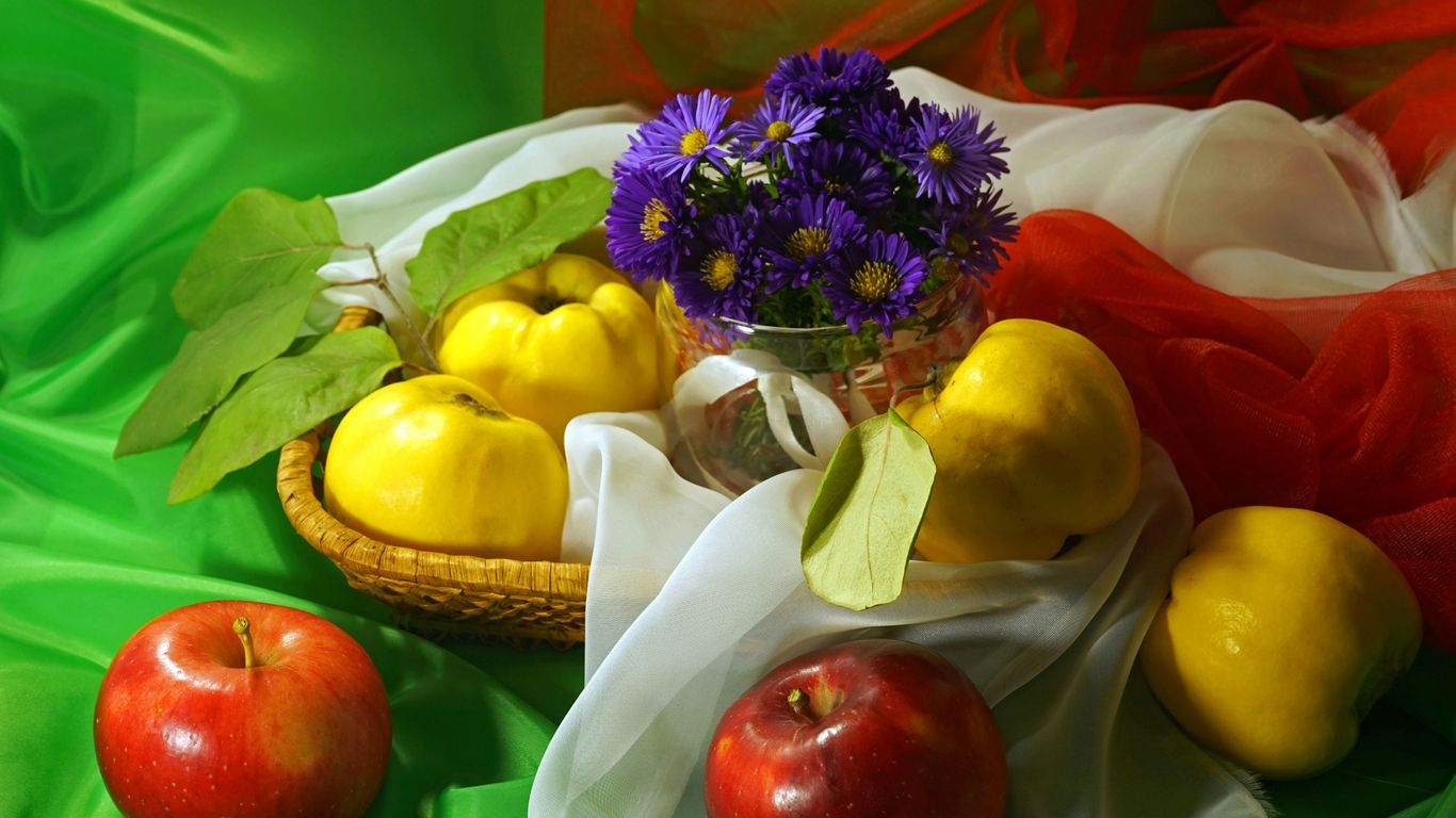a basket filled with fruit and flowers on top of a green cloth