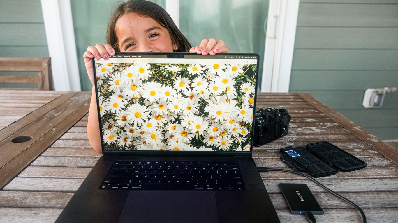 Girl peeking over laptop displaying daisies