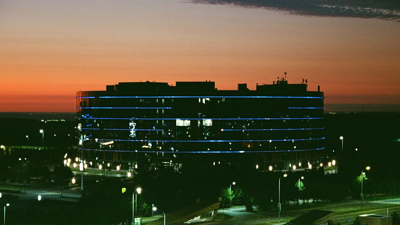 Modern office building illuminated at dusk with sunset sky.