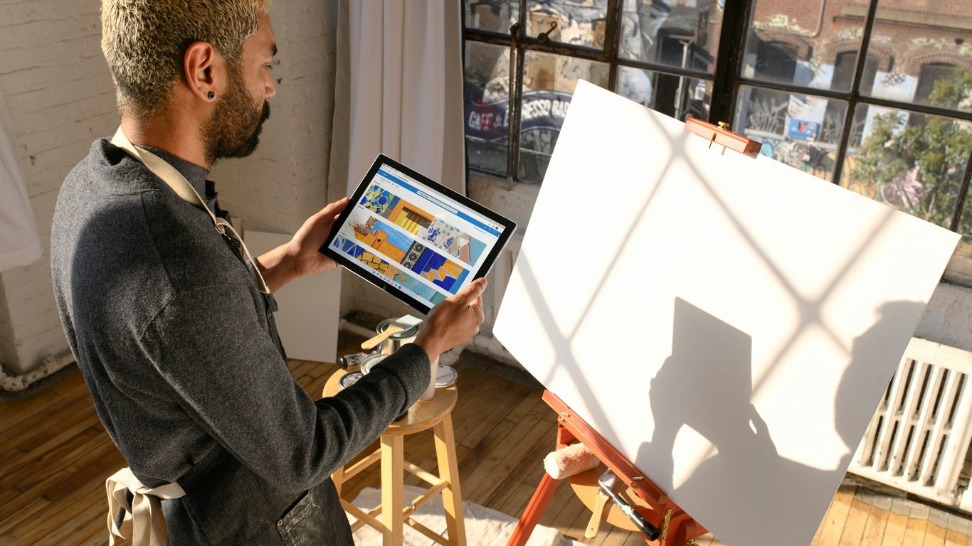 a man standing in front of an easel holding a tablet