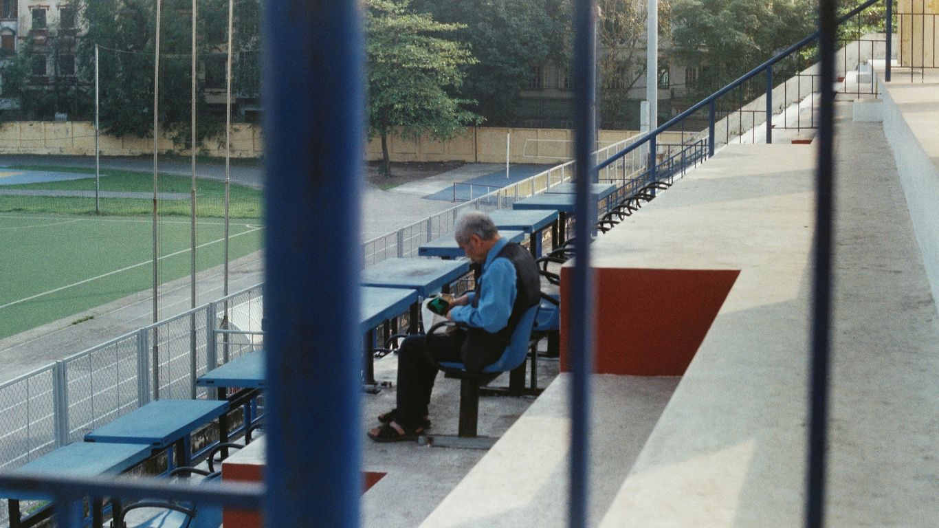 a man sitting on a bench at a baseball field