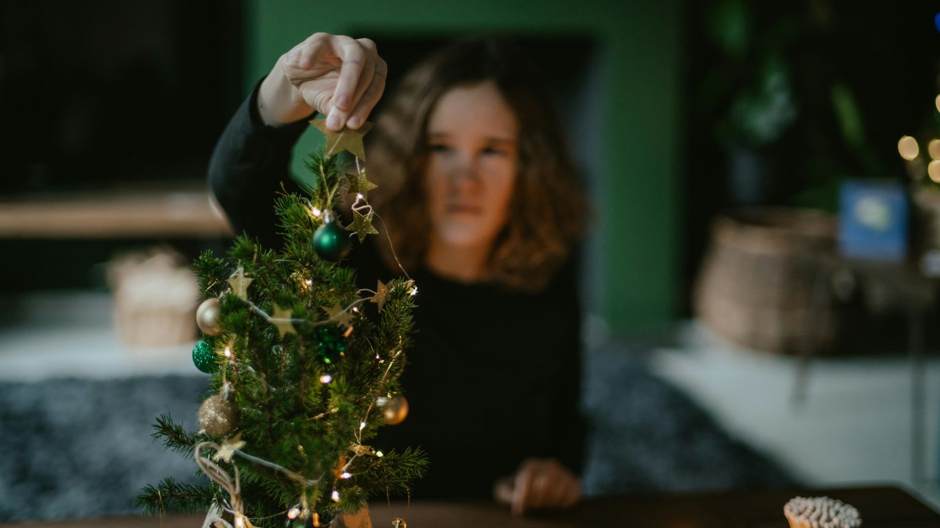 a woman lighting a christmas tree on a table