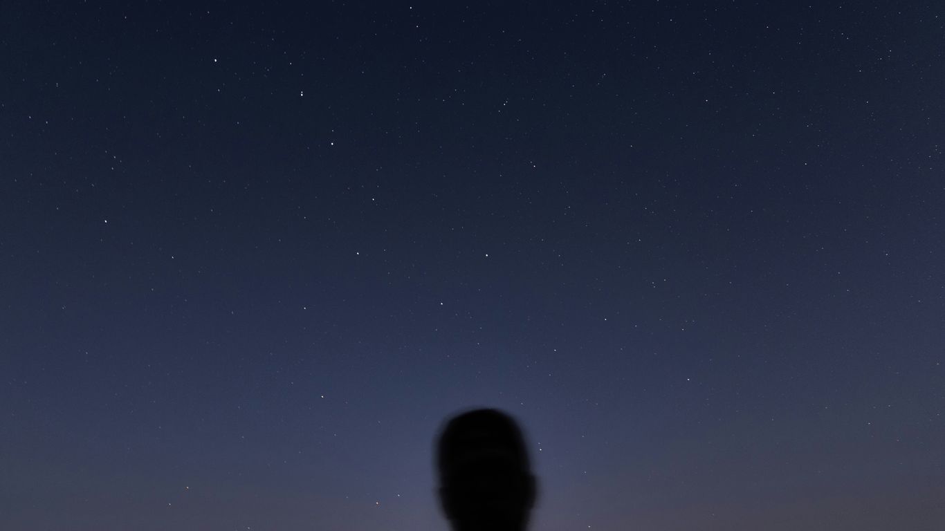 man in black jacket standing under blue sky during night time