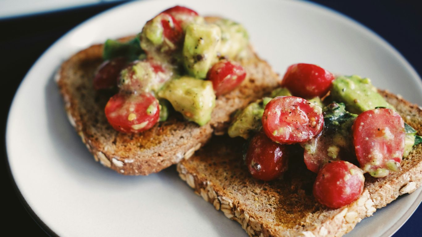 bread with tomato and green vegetable on white ceramic plate