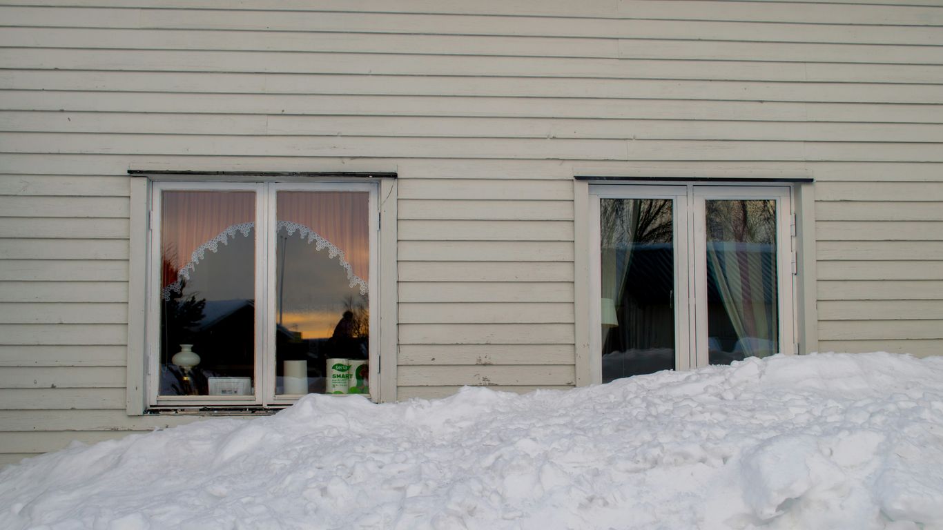 a white house with two windows and a pile of snow