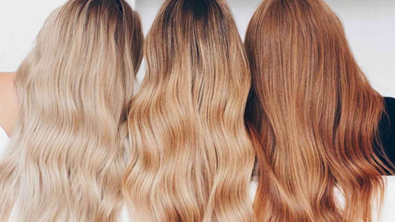 Three individuals showcasing different shades of long, wavy hair.
