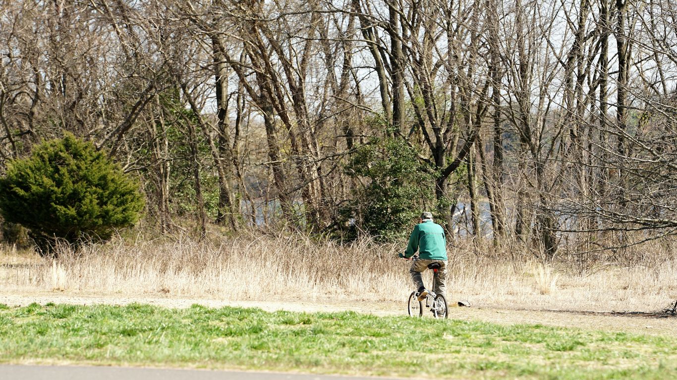 man in blue jacket riding bicycle on road during daytime