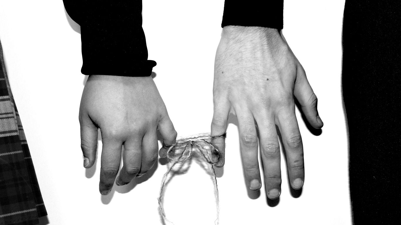 two hands holding a string tied to a tie