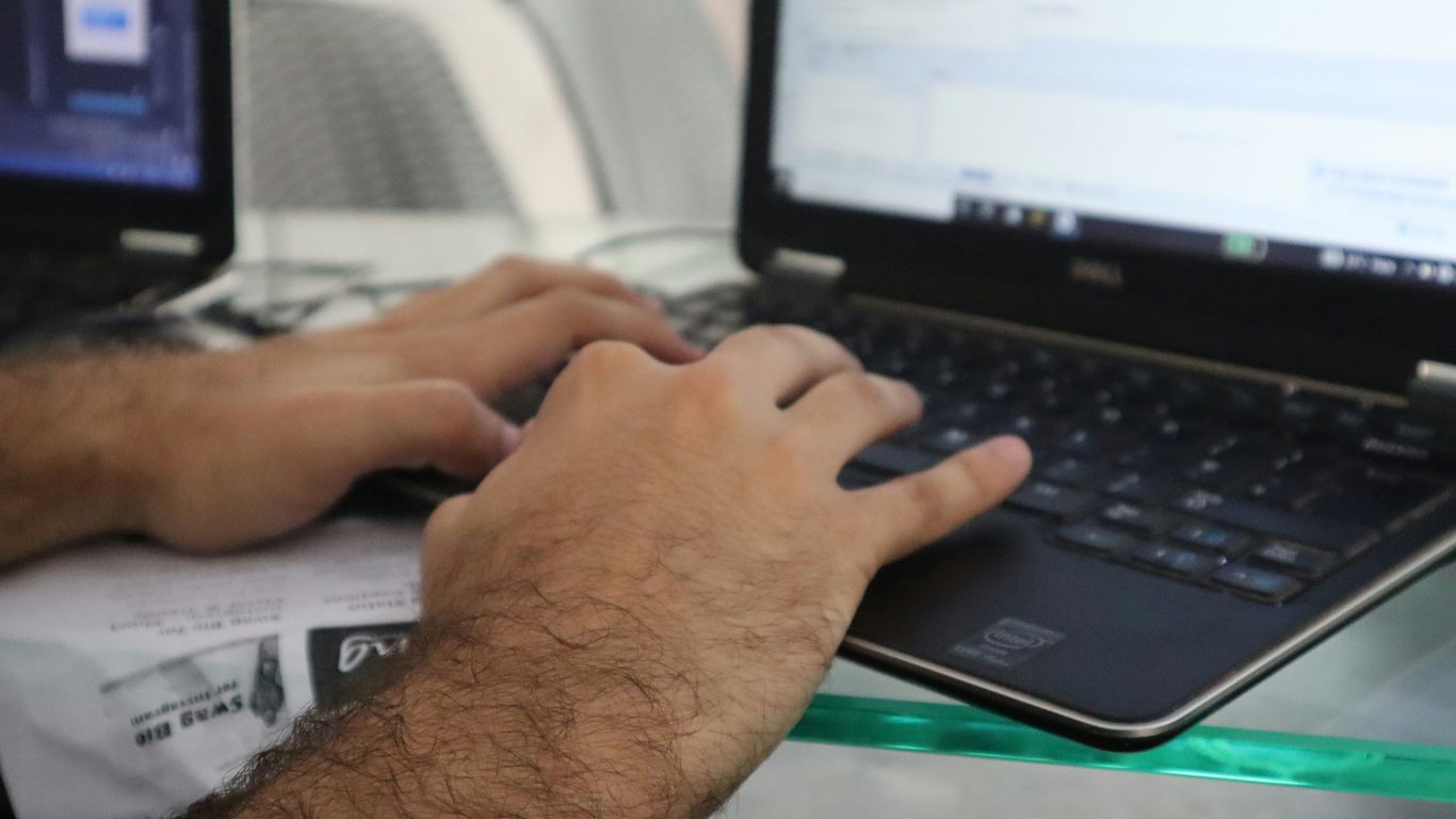 a man is typing on a laptop computer