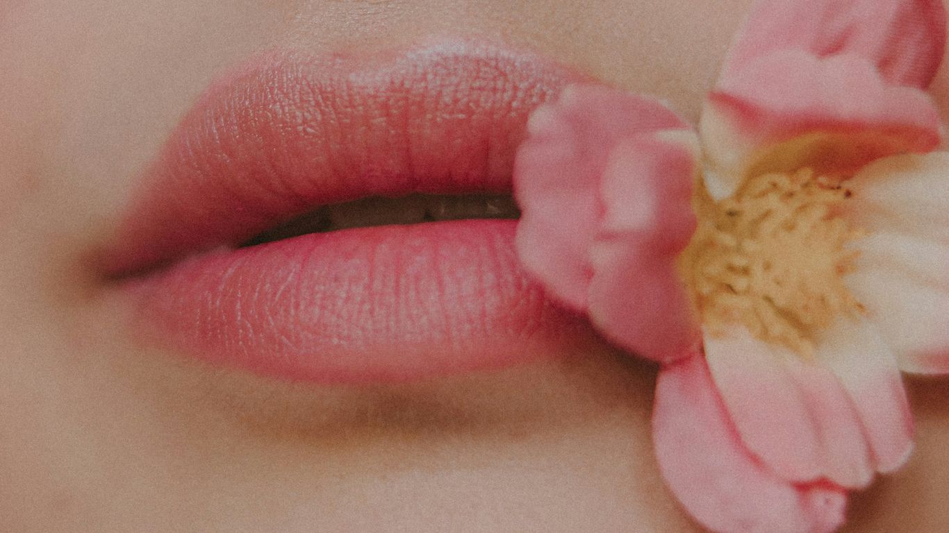a close up of a woman's lips with a flower in her mouth