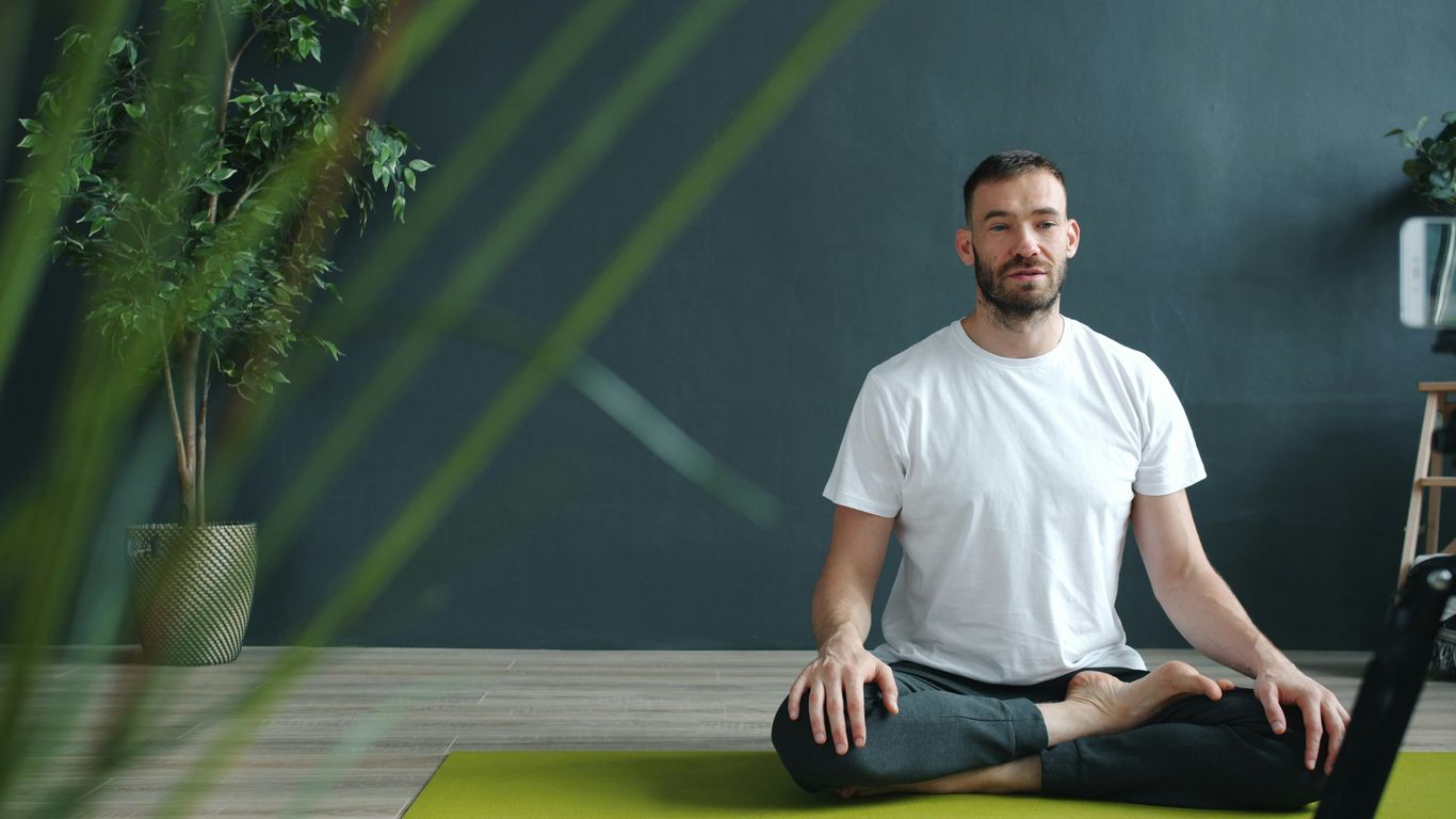 Man meditating in lotus pose on yoga mat