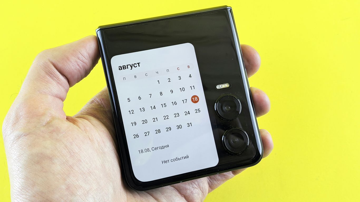 A hand holds a phone displaying a calendar.