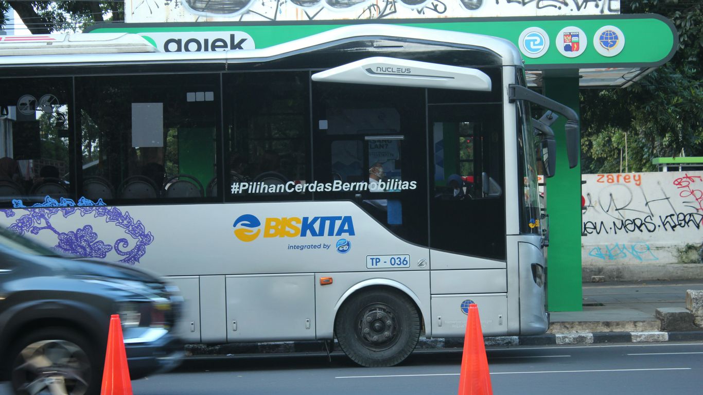 a white bus driving down a street next to traffic cones