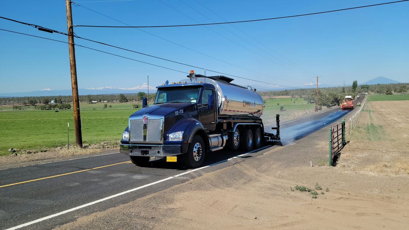a large truck driving down a road next to a field