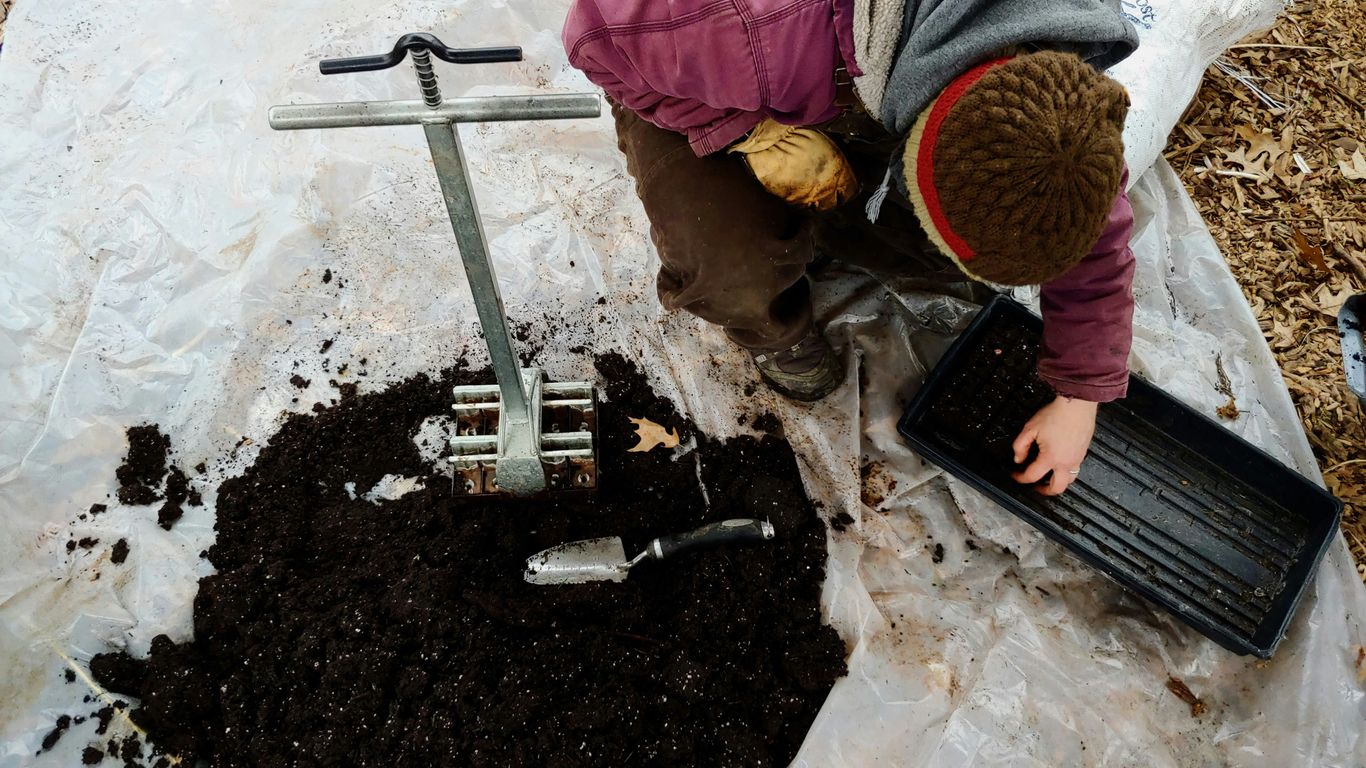 man kneeling beside black soil