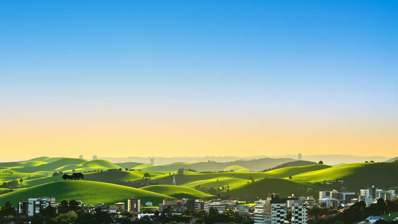 Oklahoma cityscape with rolling green hills under a blue sky.