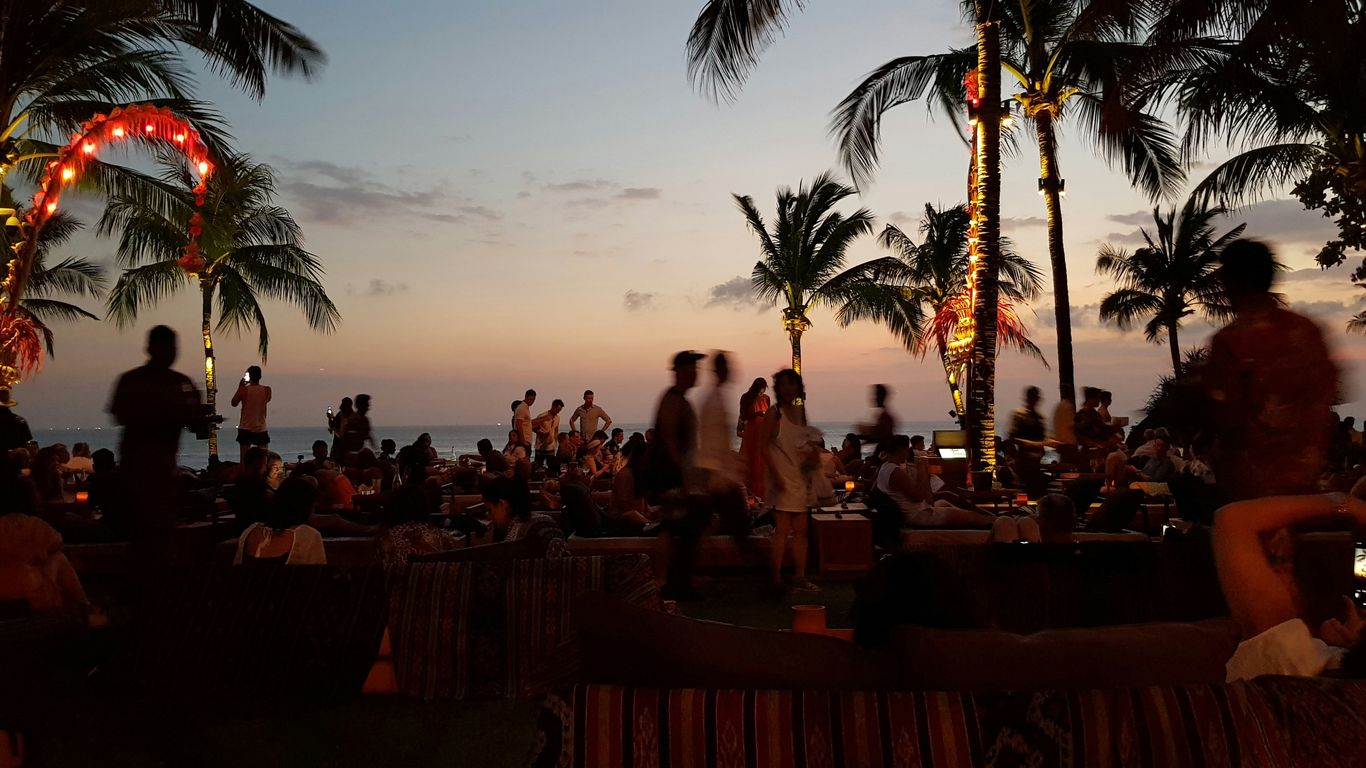 a group of people sitting on a beach at sunset