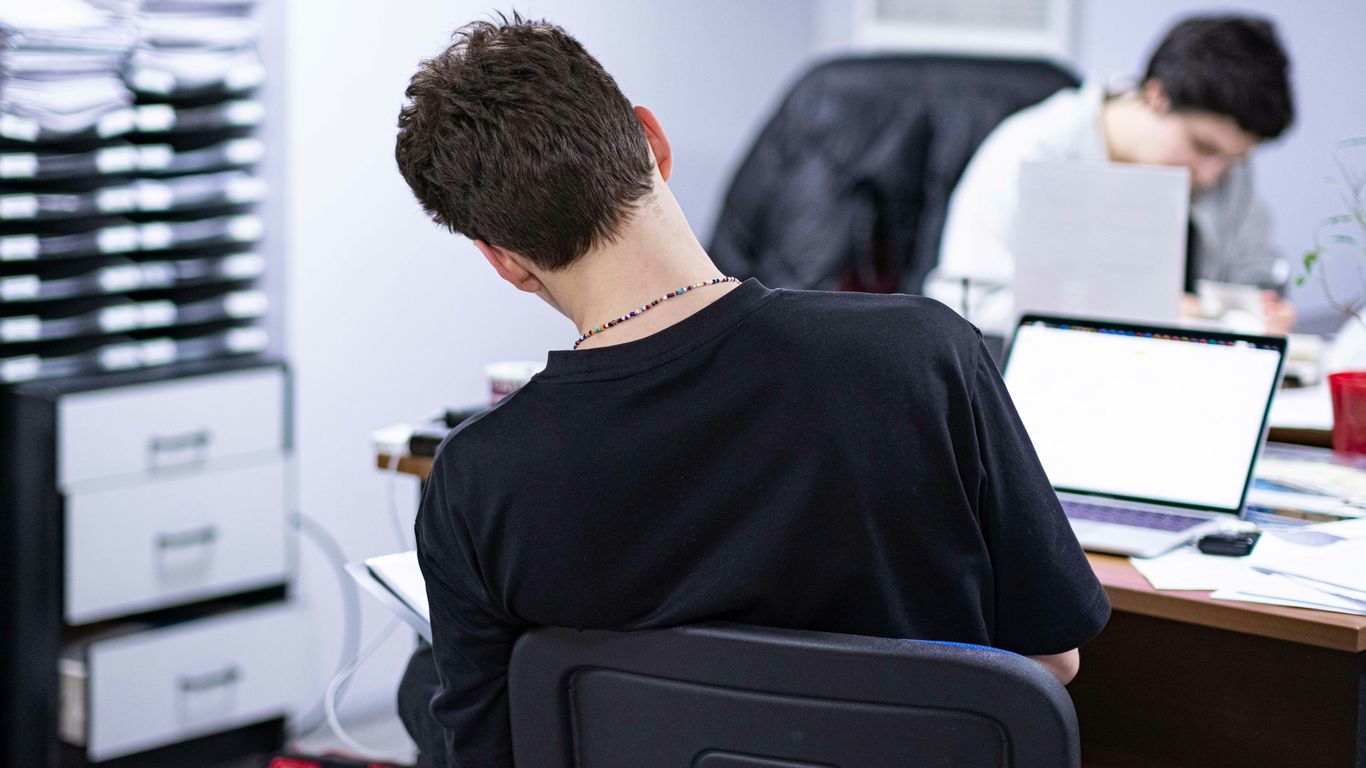 a man sitting at a desk in front of a laptop computer