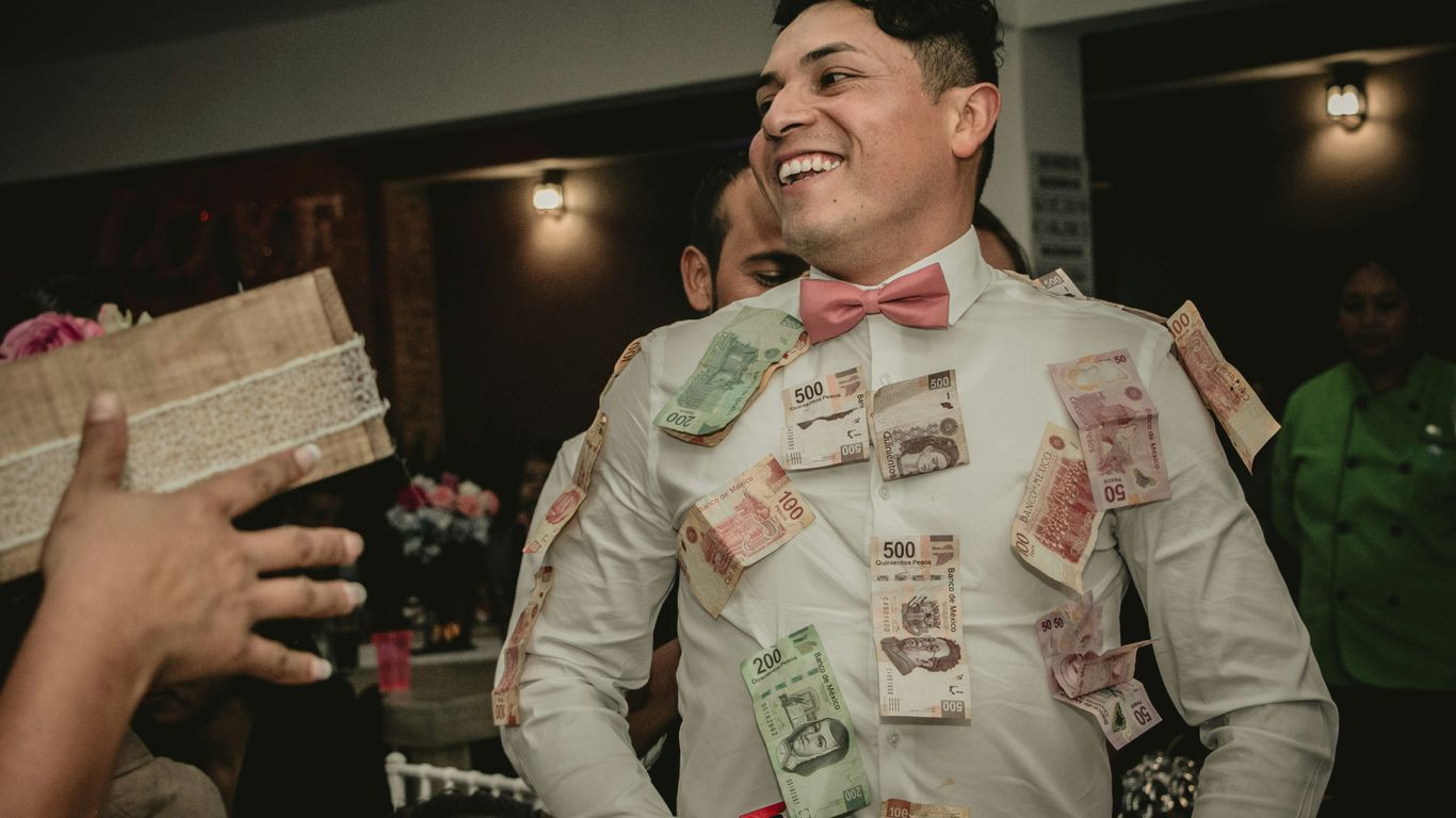 man wearing white formal suit with banknotes hanging