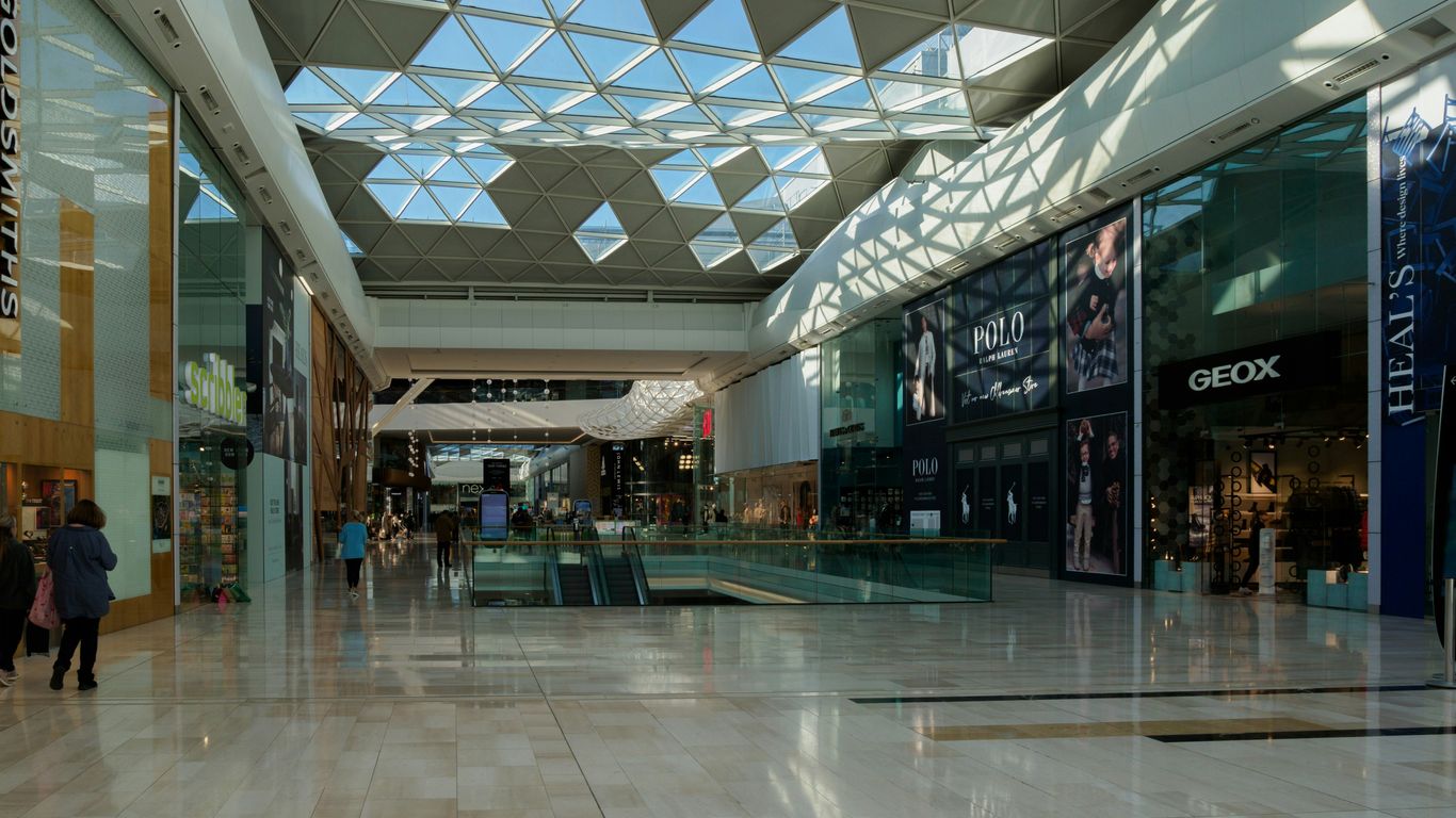a shopping mall with people walking around and a skylight