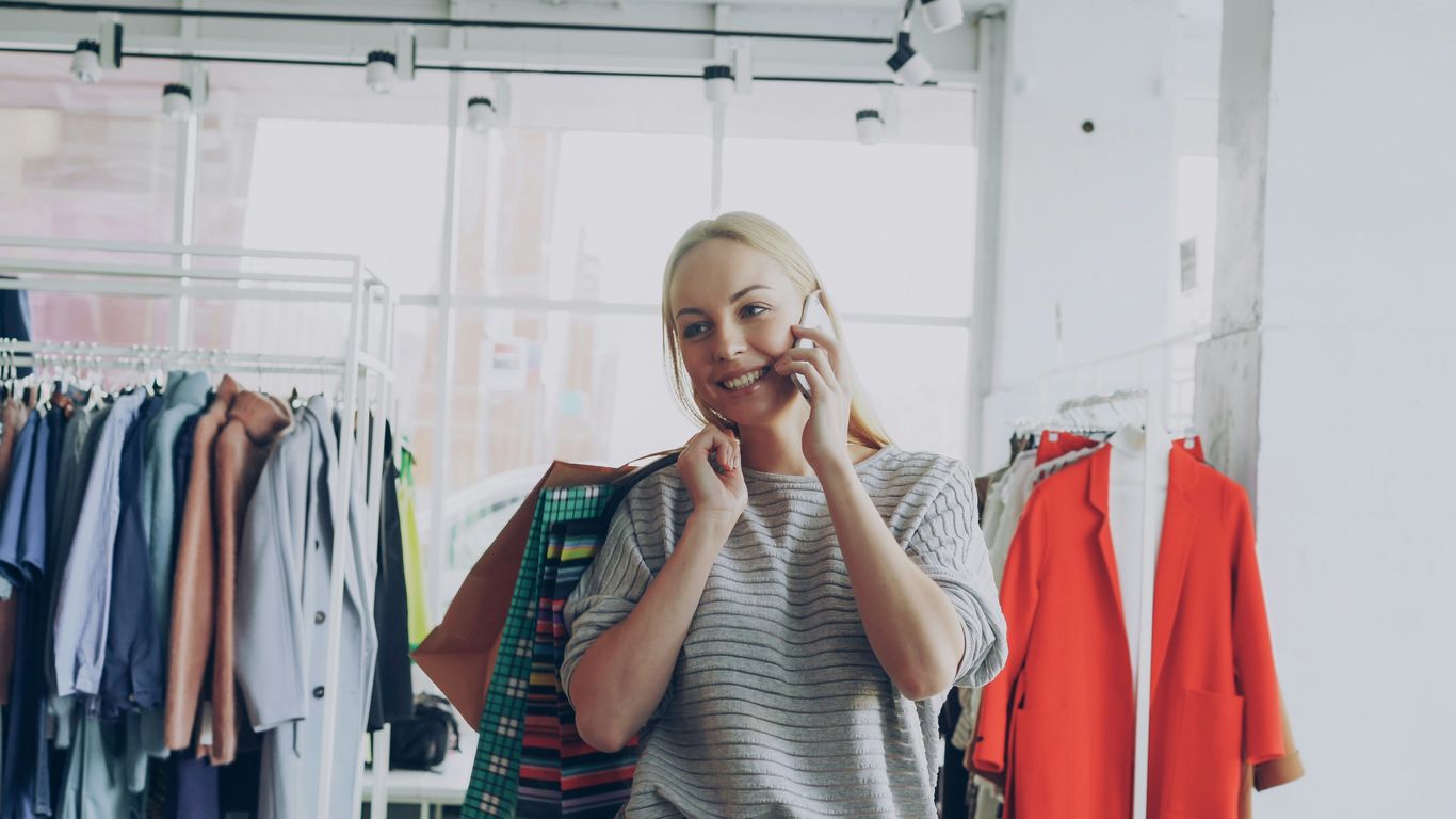 Woman talks on phone in a clothing store.