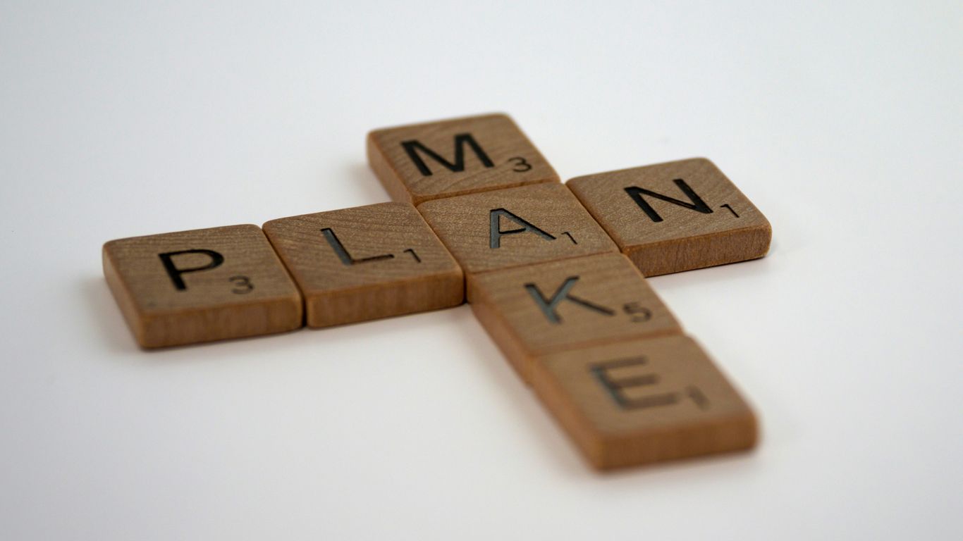 a scrabbled wooden cross with the word plan spelled on it