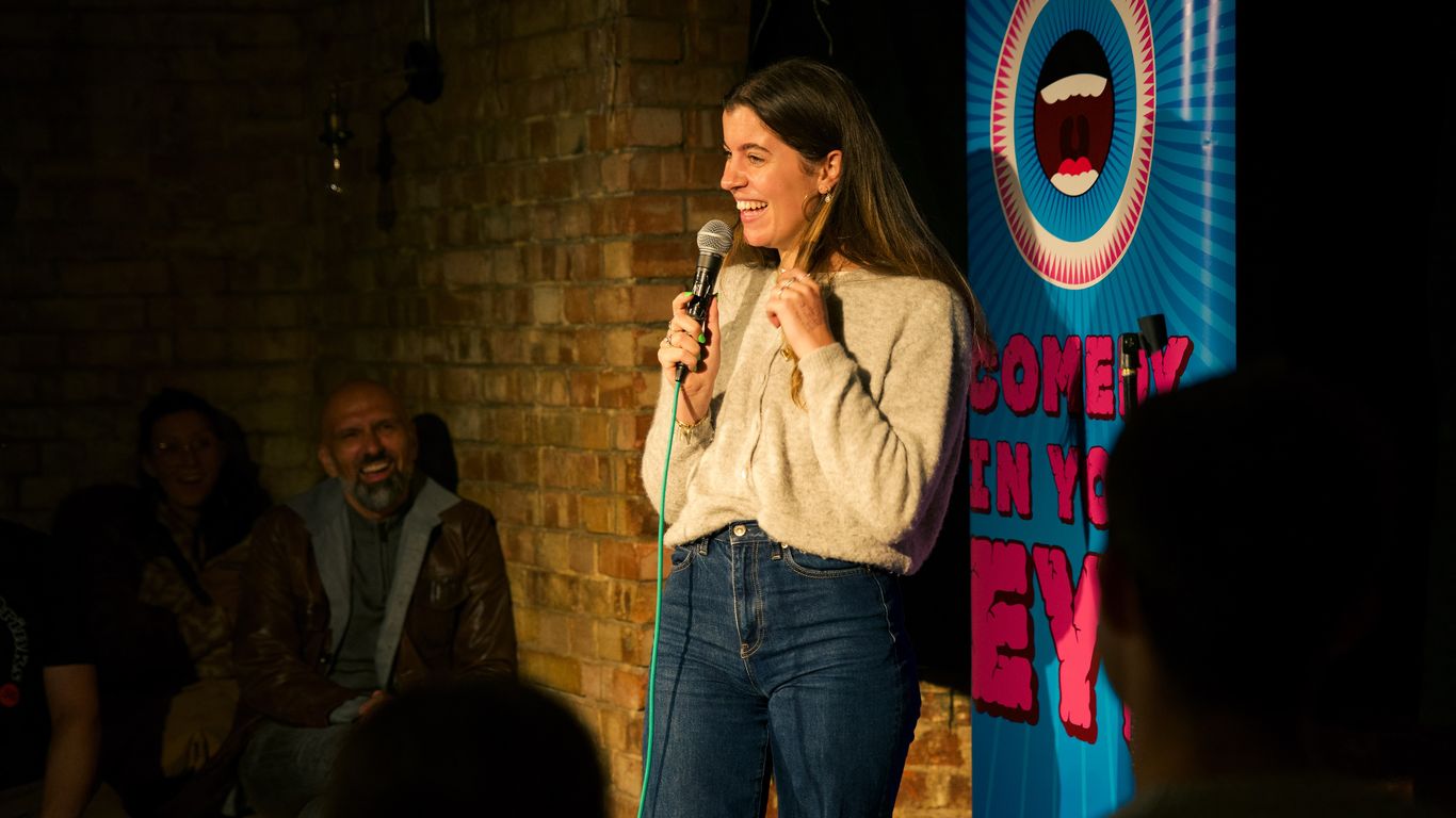 A person tells jokes on stage at a comedy club.