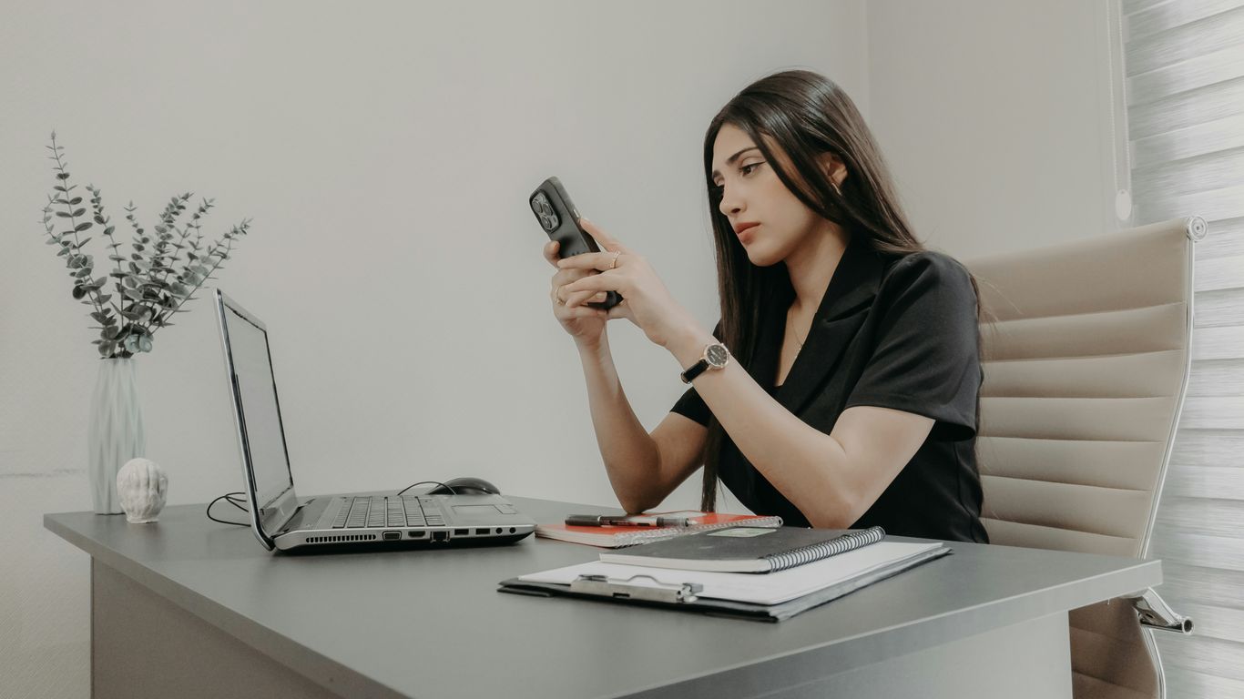 A woman using her phone at a desk