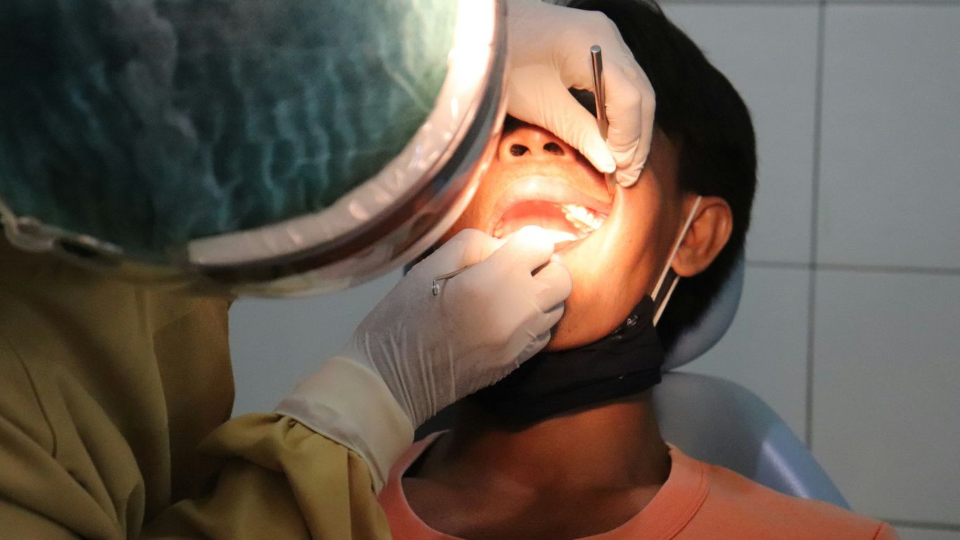 a man getting his teeth checked by a dentist