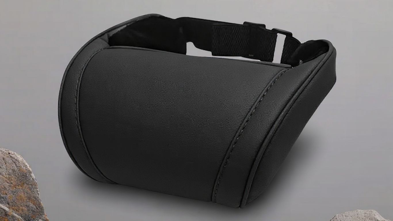 Black neck pillow placed among rocks on a neutral background.