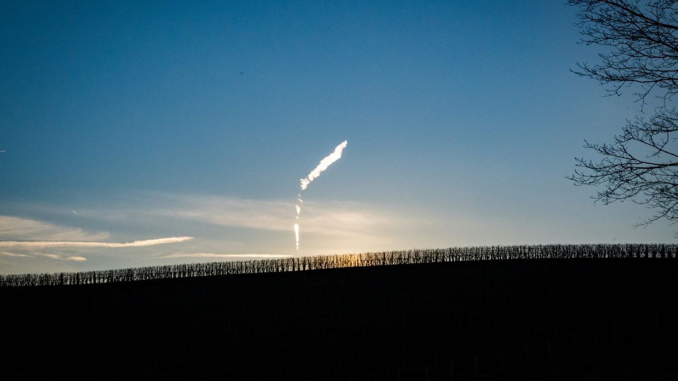 the sun is shining behind a tree in a field