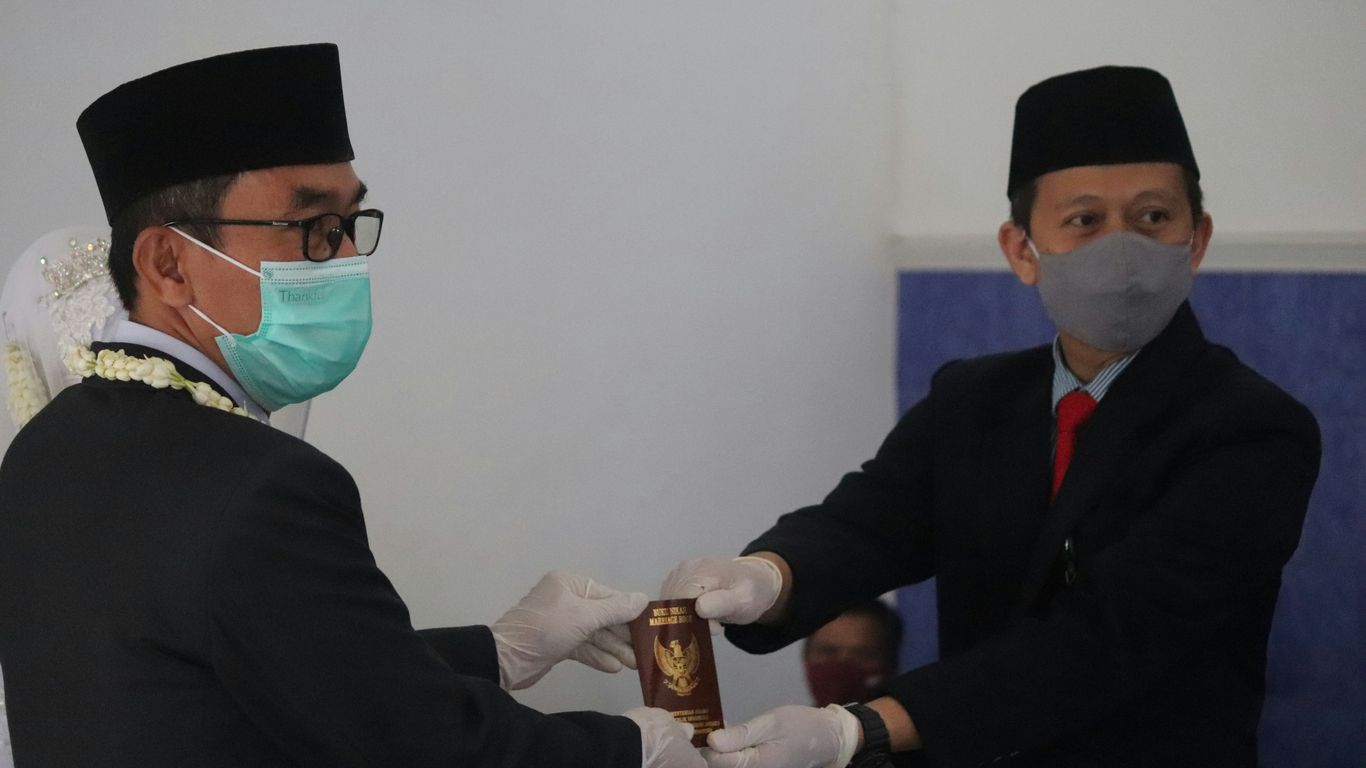 man in black suit holding glass mug