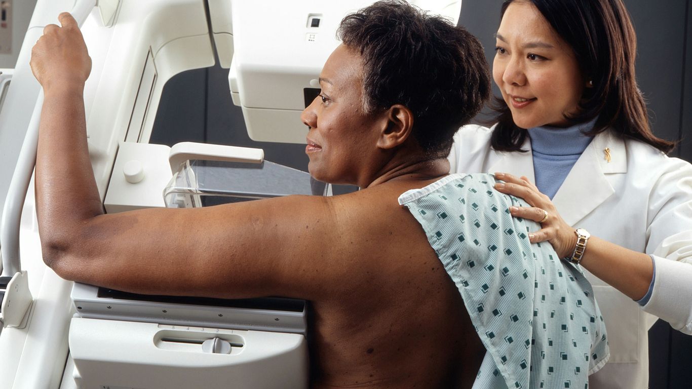 female doctor standing near woman patient doing breast cancer screening