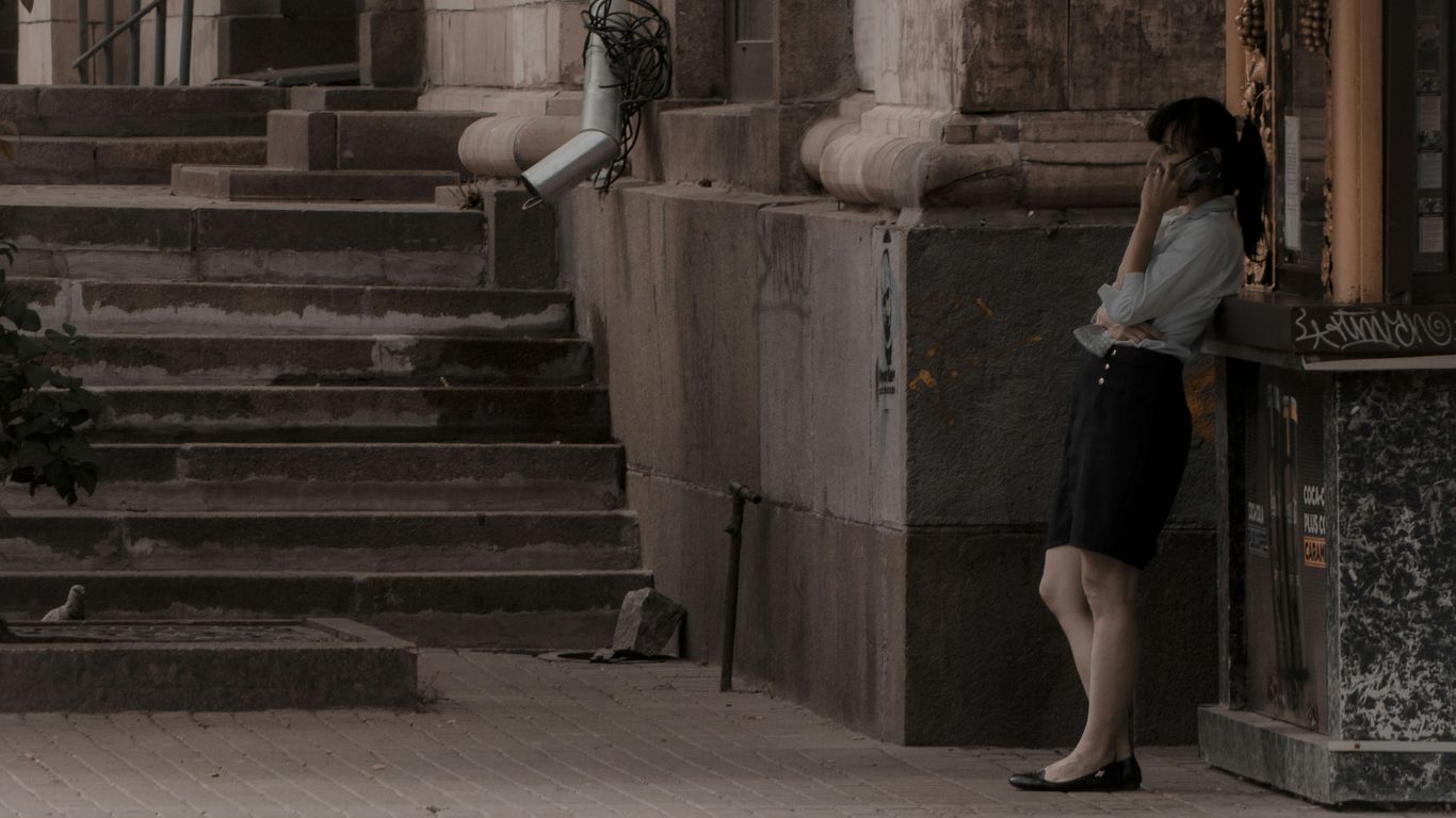 woman in white shirt and black skirt standing on gray concrete staircase